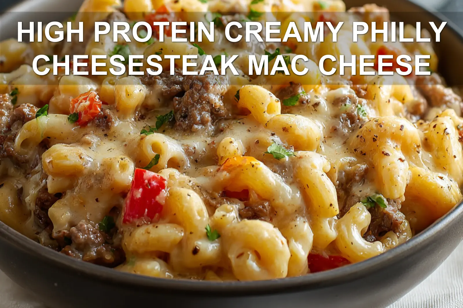 HIGH PROTEIN CREAMY PHILLY CHEESESTEAK MAC CHEESE plated bowl with melted cheese peppers and herbs