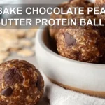 NO BAKE CHOCOLATE PEANUT BUTTER PROTEIN BALLS on wooden board with cloth and glass water
