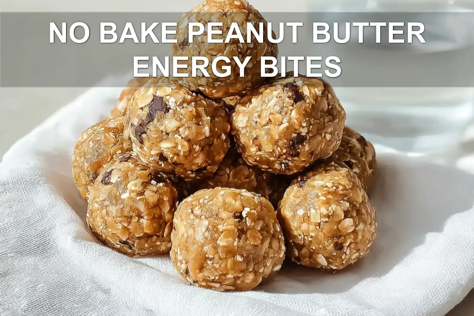 NO BAKE PEANUT BUTTER ENERGY BITES on white napkin with clear glass of water warm light