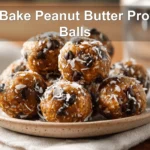 NO BAKE PEANUT BUTTER PROTEIN BALLS on white cloth with clear glass of water, warm styling