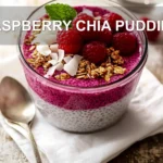RASPBERRY CHIA PUDDING topped with raspberries sliced almonds coconut flakes maple syrup and mint