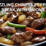 SIZZLING CHINESE PEPPER STEAK WITH ONIONS served with steamed rice green onions vibrant peppers