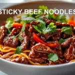 STICKY BEEF NOODLES close-up plated with sesame and green onions, warm natural light