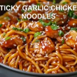 STICKY GARLIC CHICKEN NOODLES glazed chicken and noodles in warm bowl with green onions