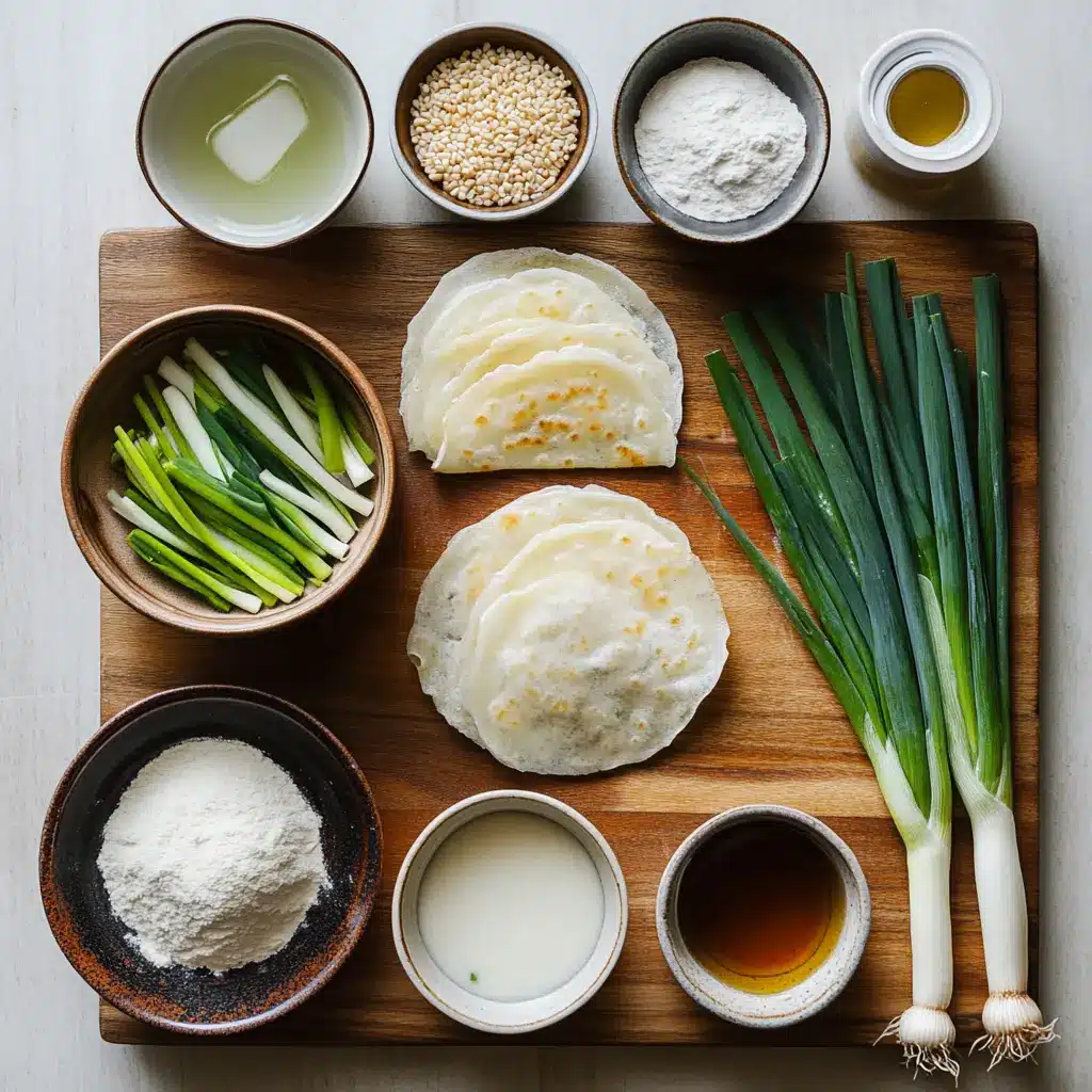 Fresh scallions, flour, potato starch, and other ingredients for Pajeon Korean Scallion Pancake laid out on a rustic wooden surface.