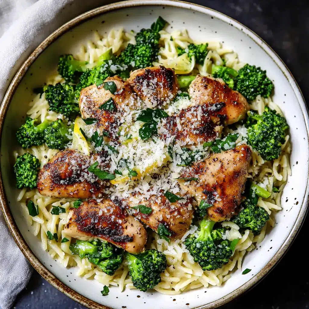 Lemon Pepper Chicken Broccoli Orzo in a white bowl with fresh herbs, centered hero view